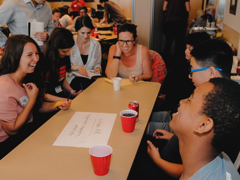 men and women smiling around table