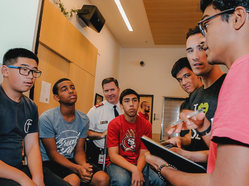 Man speaking to youth sitting in chairs