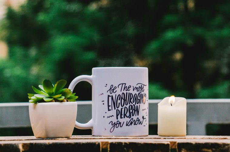 coffee cup on table next to plant and candle