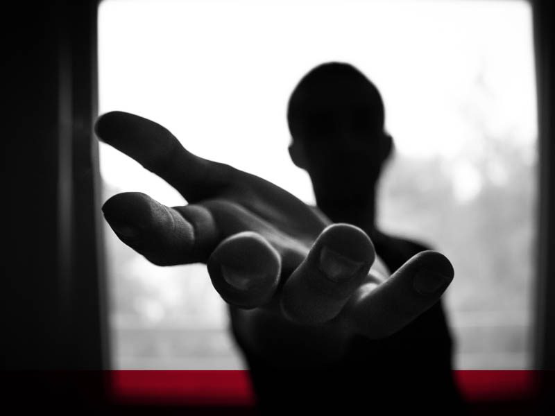 Silhouette of person reaching hand out