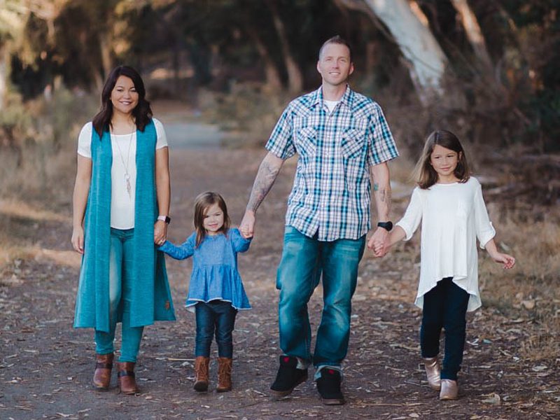 Mom, dad, and two daughters walking on road