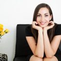 Woman sitting on couch next to flowers