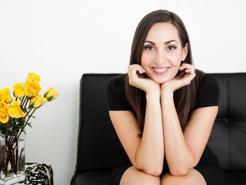 Woman sitting on couch next to flowers