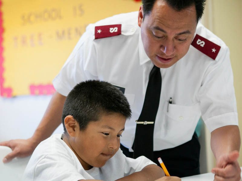 Salvation Army soldier helping child doing homework