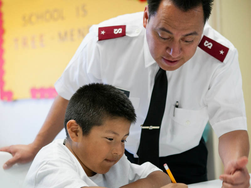 Salvation Army soldier helping child doing homework