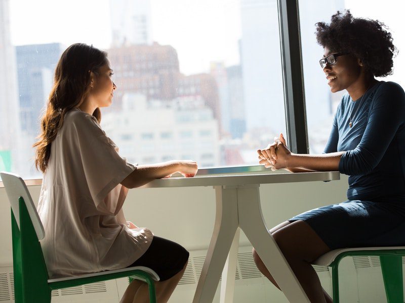 two women talking at a table together