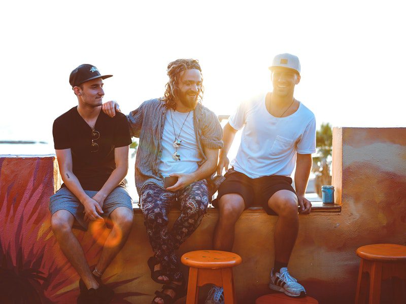 three men sitting on ledge outside