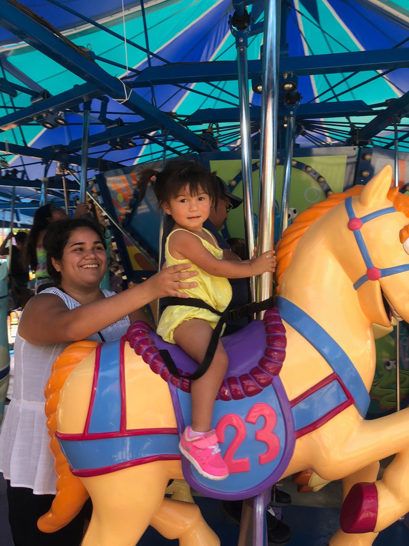 mother supporting daughter on merry-go-round