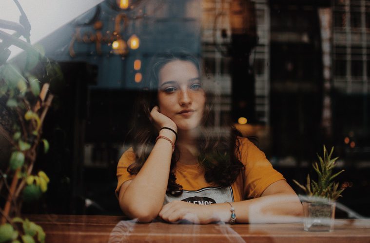 view of woman sitting alone through glass