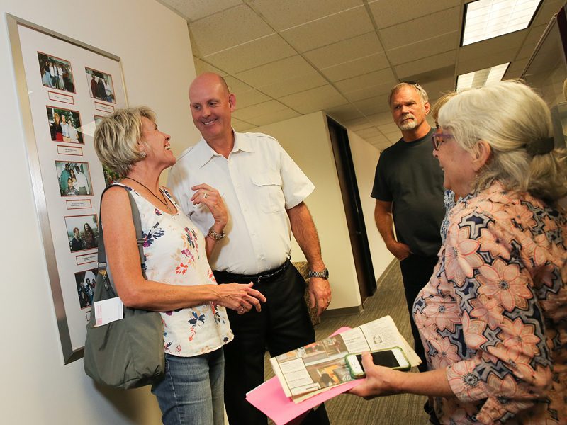 Man and woman smiling at each other in hallway with other people 