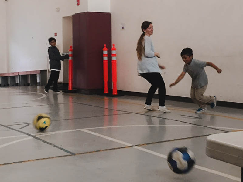 Elizabeth Veras Holland playing soccer with children