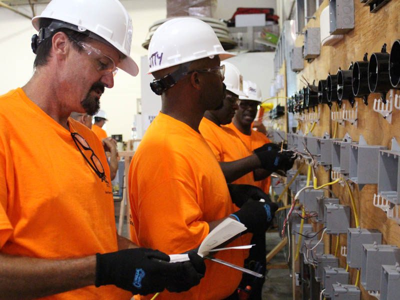 Men in orange shirts and hardhats working