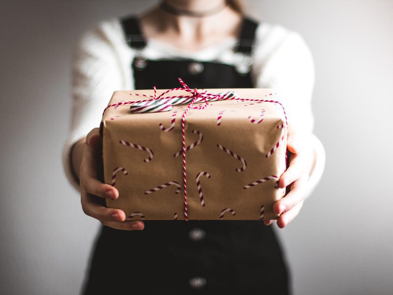 woman holding presents with candy cane wrapping paper