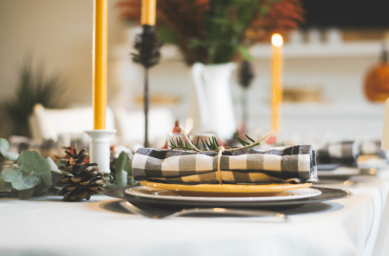 Single table setting on white table cloth in front of candles