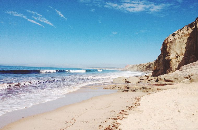 shore and water next to rock formation