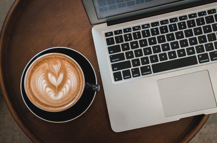 Coffee cup next to laptop