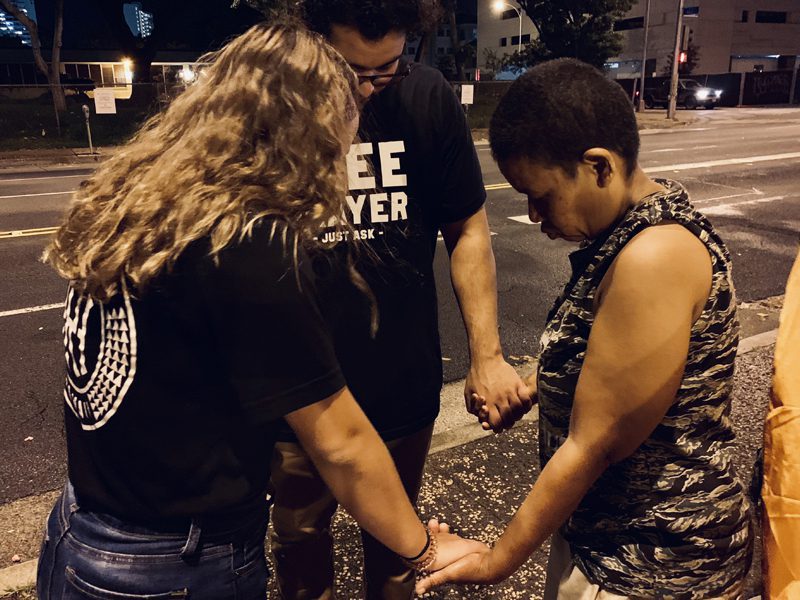 Homeless woman Praying with Sandwich Ministry members
