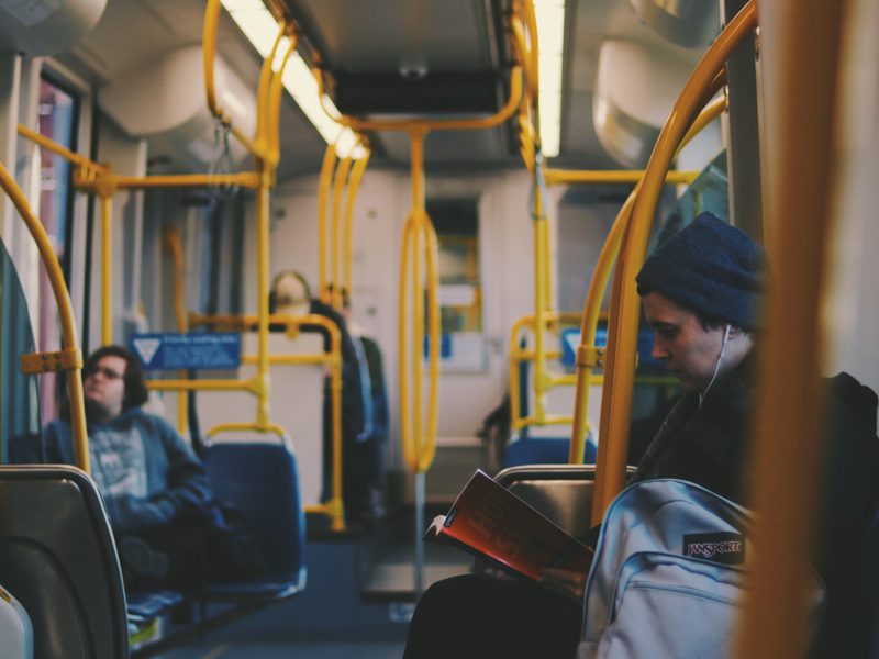 Closeup of man reading on bus with headphones in.