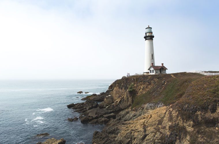 Lighthouse on Edge of Cliff Next to Water