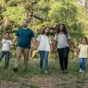 Family Holding Hands Walking Through Field