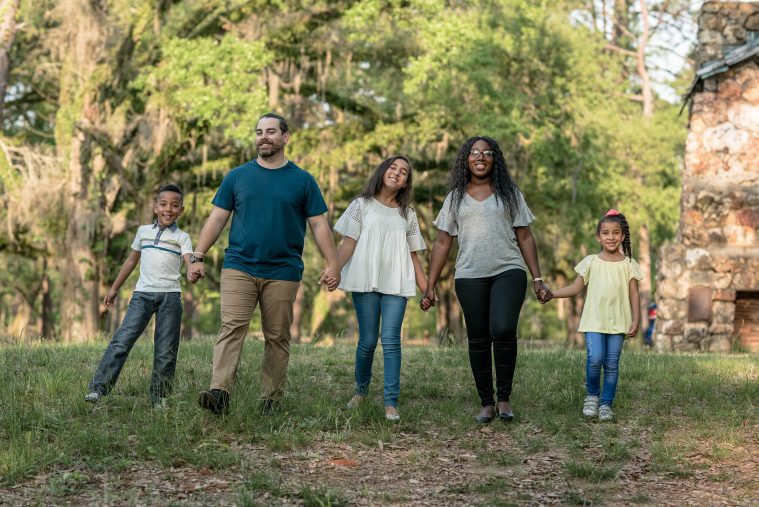 Family Holding Hands Walking Through Field