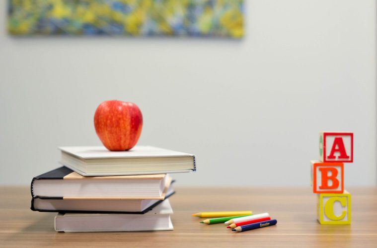 Apple on Books Next to Pencils and Alphabet Blocks