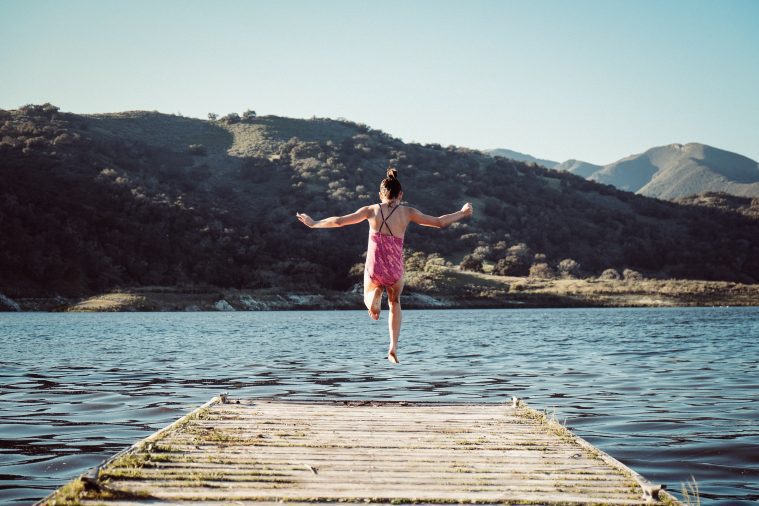 Young Girl Jumping Off Dock into Lake