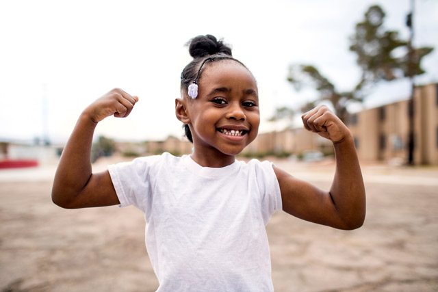 Female child smiling and showing muscles