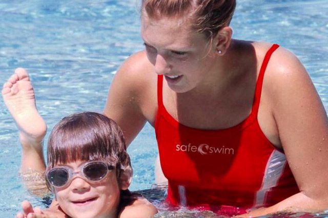 Lifeguard giving child swimming lesson