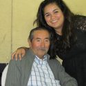 Granddaughter smiling with grandfather who is sitting