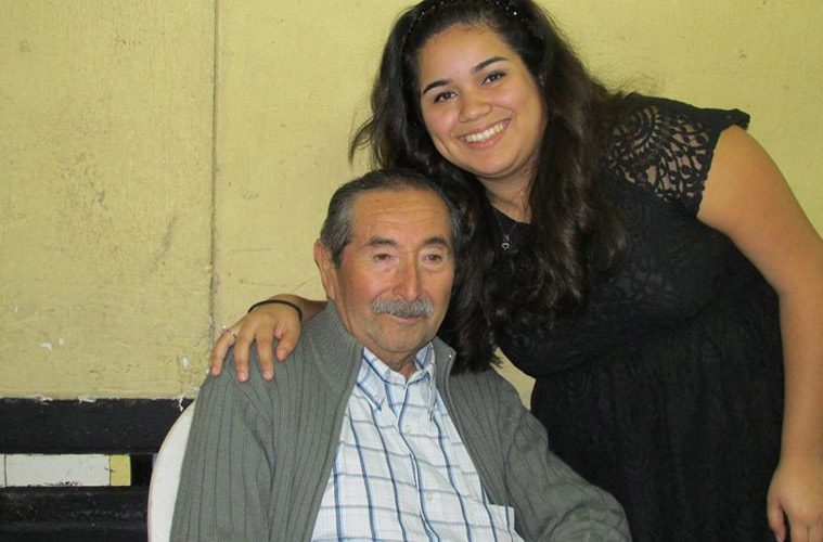 Granddaughter smiling with grandfather who is sitting