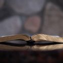 Open Bible on Table in Front of Stone Wall