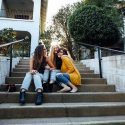 Three female friends laughing together while sitting on stairs