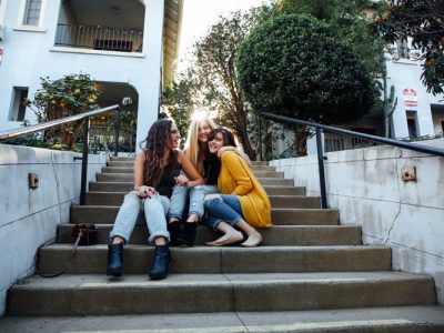 Three female friends laughing together while sitting on stairs