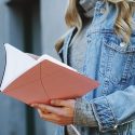 Woman in jean jacket holding open book