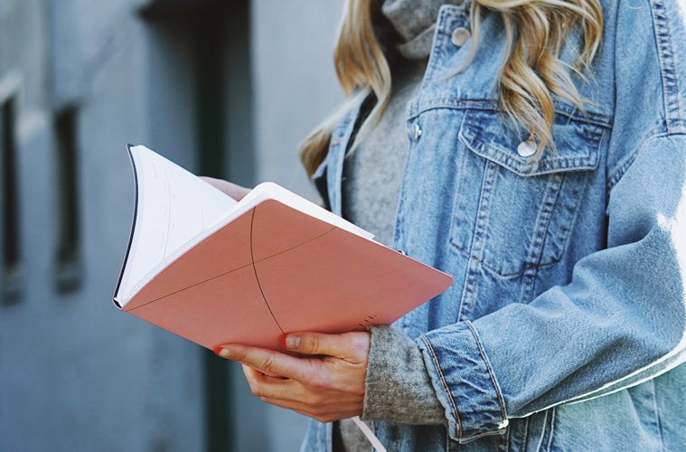 Woman in jean jacket holding open book