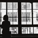 black and white photo of woman looking outside window