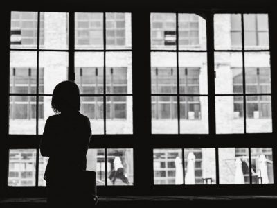 black and white photo of woman looking outside window