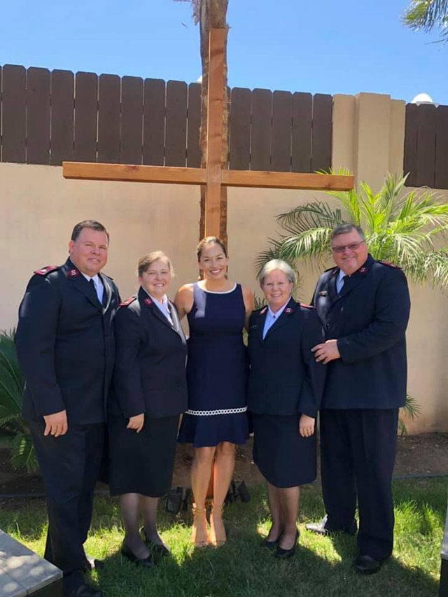 Salvation Army Members along with Alyssia Neill Peters Stand Together in Front of Cross