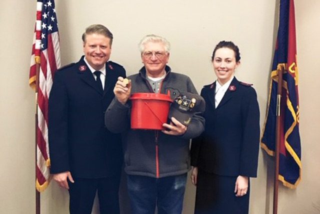 Man holding Krugerrand and kettle with Salvation Army soldiers