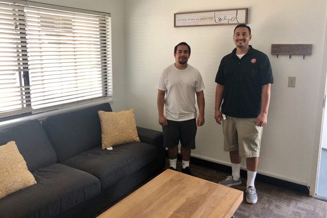 Two men standing next to table and couch