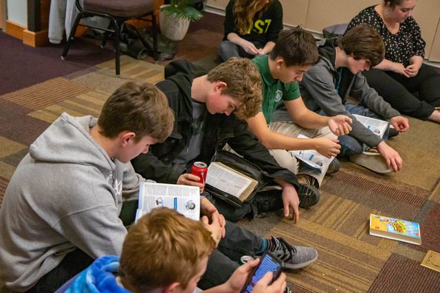 Kids sitting on floor reading Bible