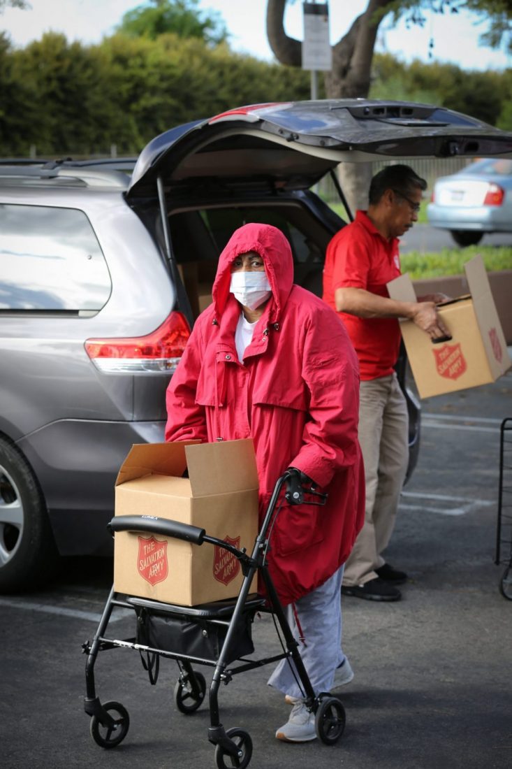 Woman with mask on pushing cart with box in it