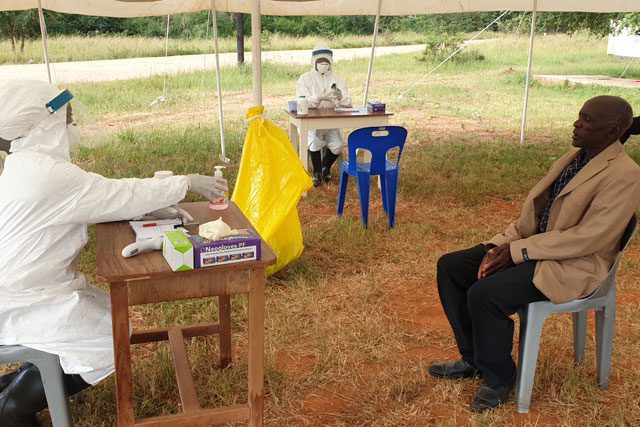 Doctor in protective clothing speaking to man