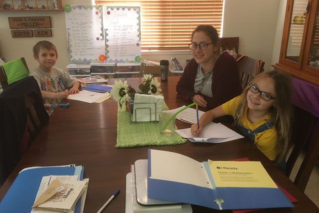 Librarian with young boy and girl working at table