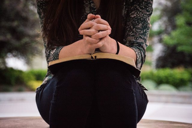 Hands folded on top of Bible