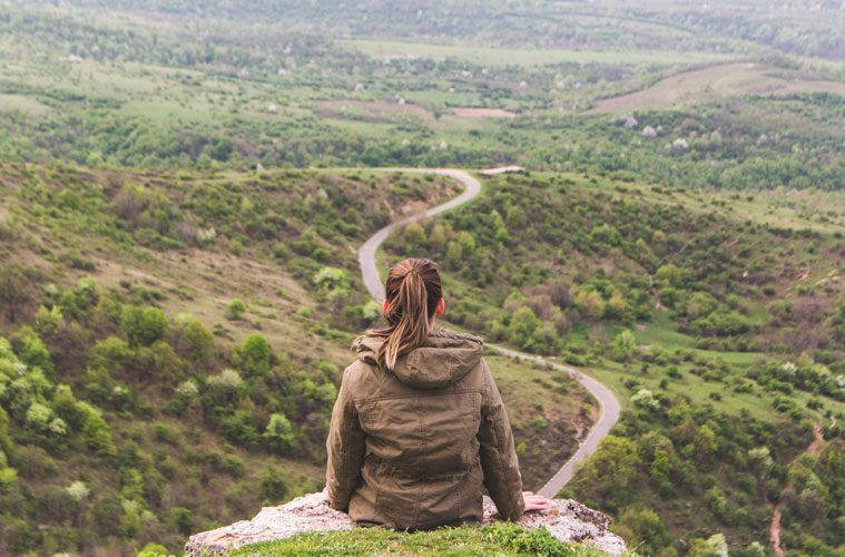 Woman sitting at edge of cliff