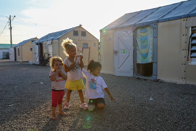 Three migrant girls outside in refugee camp