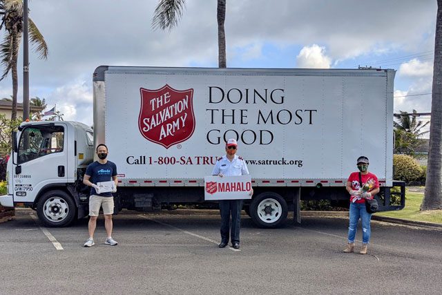 Officer and two volunteers holding sign in front of Salvation Army truck