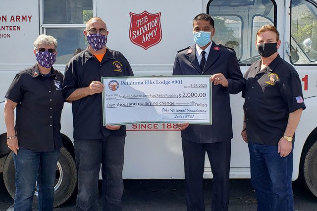Men with masks holding donation check